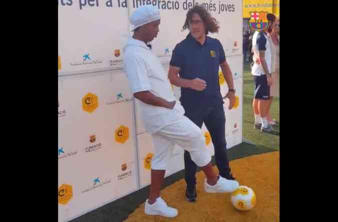 Aproveitando o momento de distrao de Carles Puyol, o ex-craque brasileiro Ronaldinho Gacho d uma 