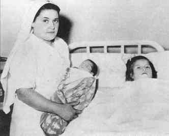 A jovem peruana Lina Medina posa deitada na cama do hospital em que deu  luz o filho Gerardo, que est no colo da enfermeira(foto: Elitereaders.com/Reproduo)